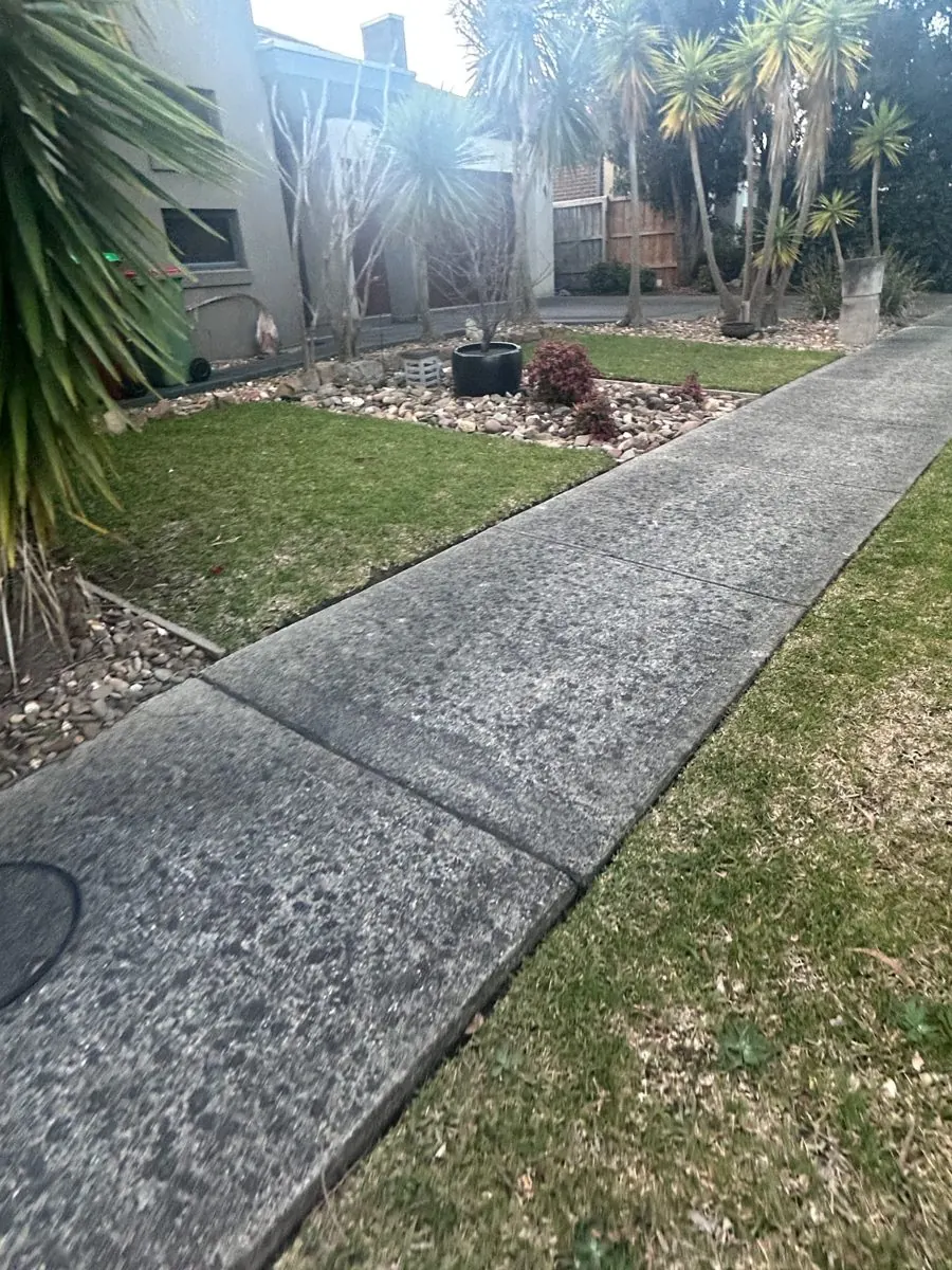 Front yard mowing — Berwick. Front lawn mown both sides of the concrete path and trimmed neatly around the pebble garden beds.