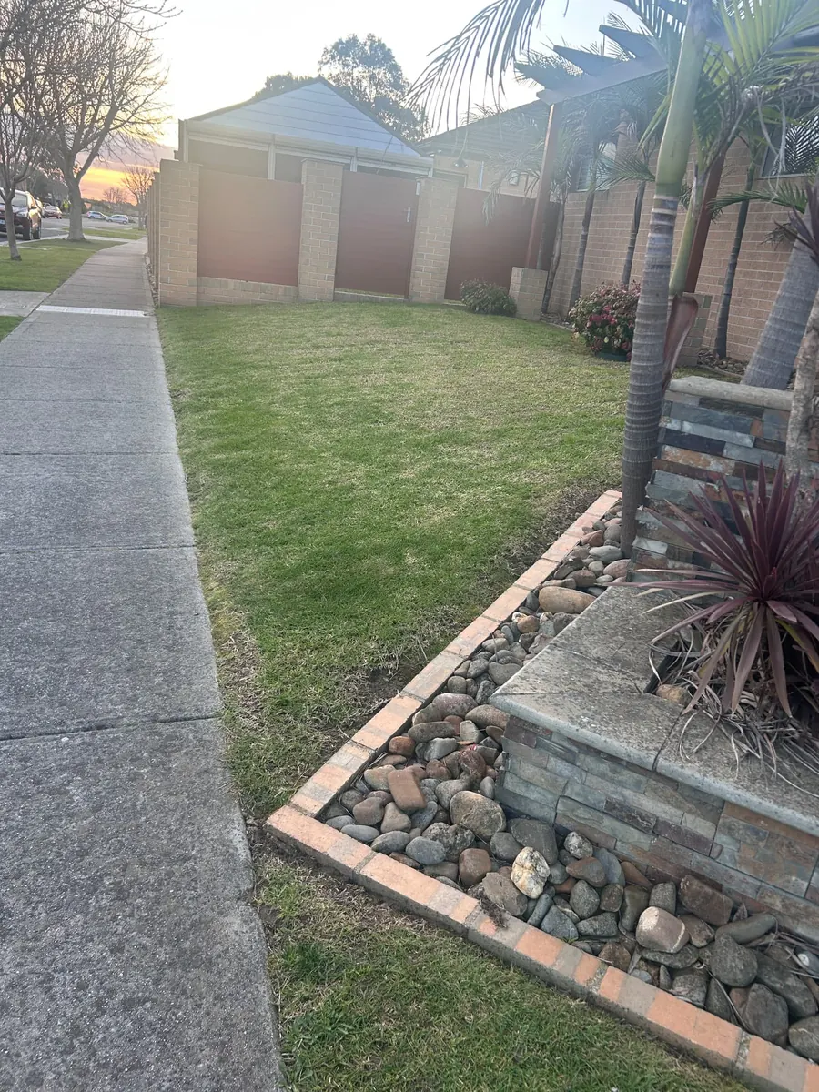 Freshly mown Berwick front yard beside a curved stone garden bed